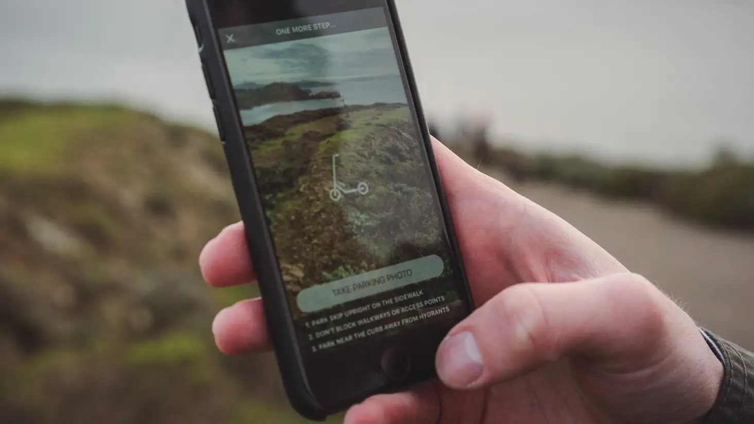A phone taking a photograph to note the location of the scooter on a hilltop.